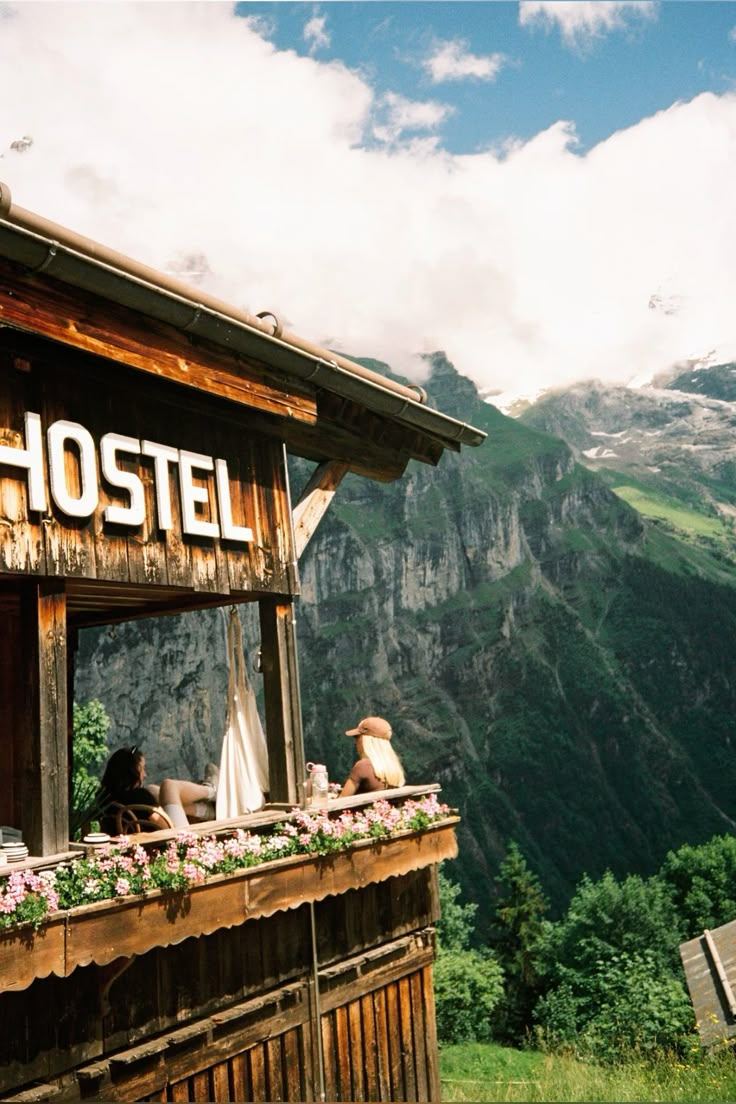 Alpine hostel balcony with a HOSTEL sign and mountain views