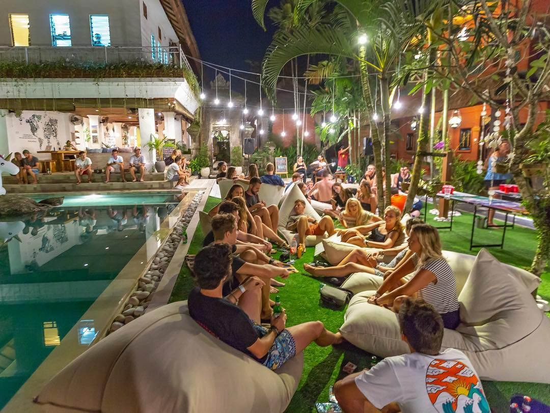 Travellers hanging out together at a hostel pool party at night