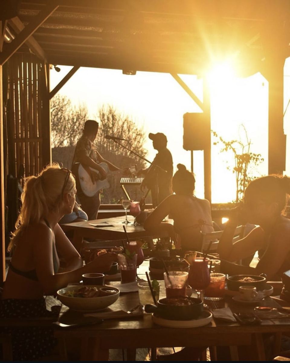 Friends sharing a sunset dinner with live music at a beach bar