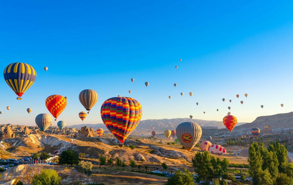 Hot air balloons rising over the Cappadocia landscape at sunrise