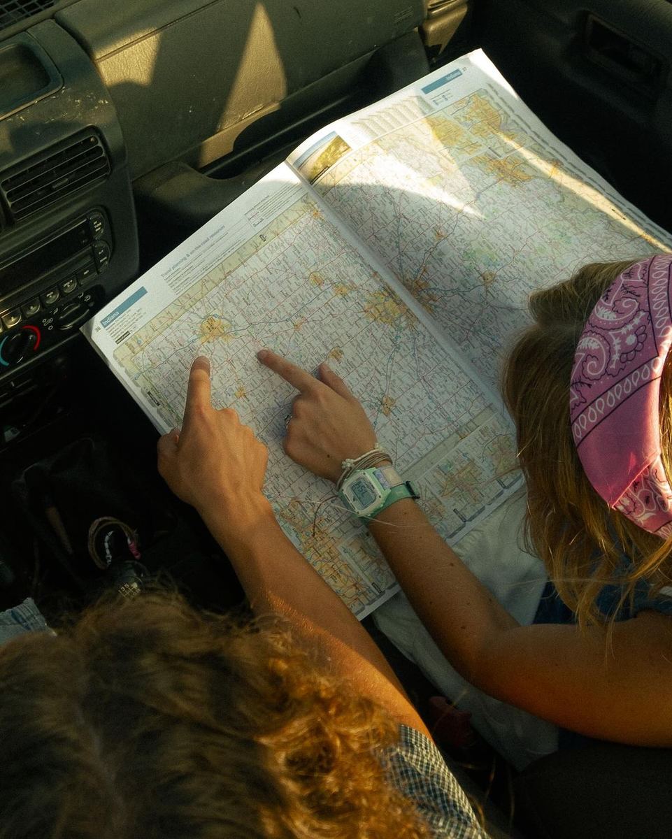 Friends planning a road trip route on a paper map in the car