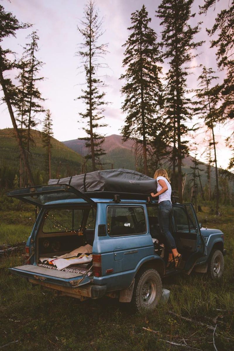 4x4 with a rooftop tent parked in the forest at dusk